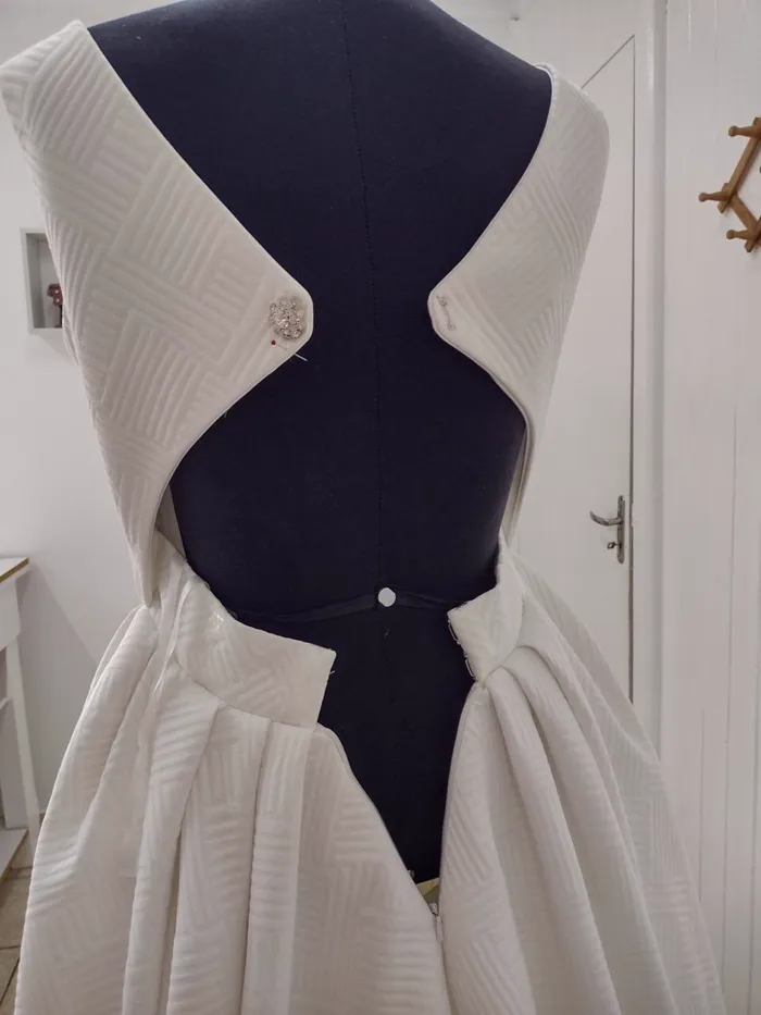 Vestido de noiva ainda preso com alfinete no manequim, sem acabamento nas costas